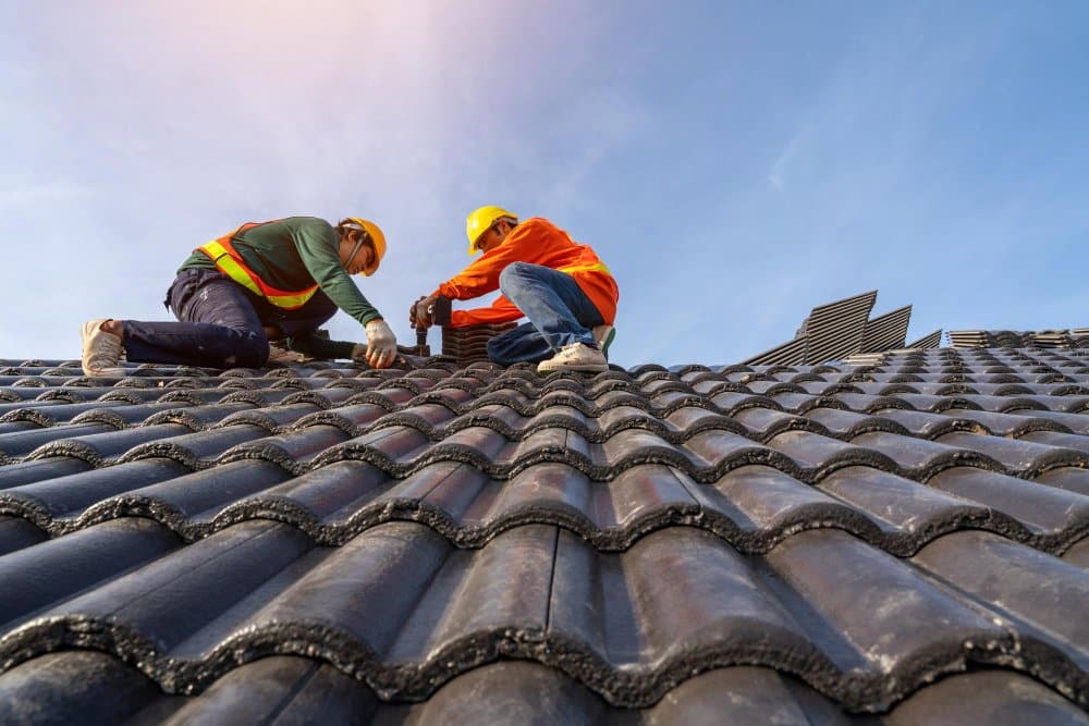 Roofers laying black shingles