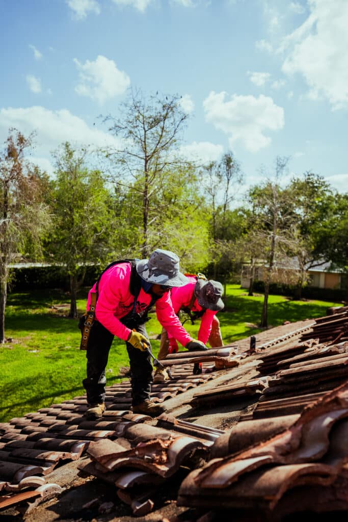 Two roofers removing old tile roof